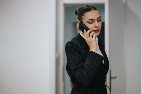 Professional woman in business suit talking on a mobile phone indoorsの写真素材