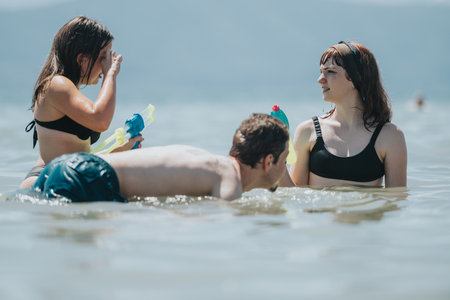 Friends enjoying a playful water fight in shallow beach waters on a sunny day
