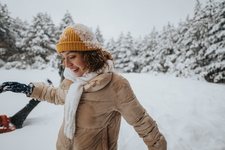 Woman Enjoying a Winter Day Outdoors in the Snowy Forest Wearing a Warm Hatの写真素材