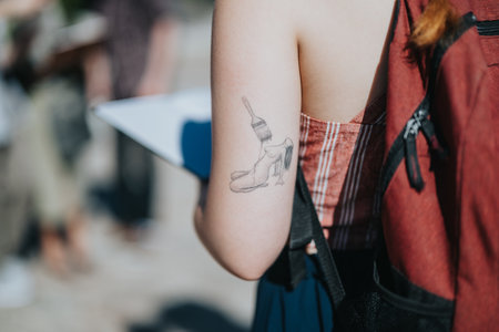 Close-up of person with tattoo in a sunny courtyard settingの写真素材
