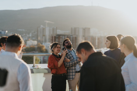 Cross generational, business colleagues celebrating success on a balcony during sunsetの写真素材