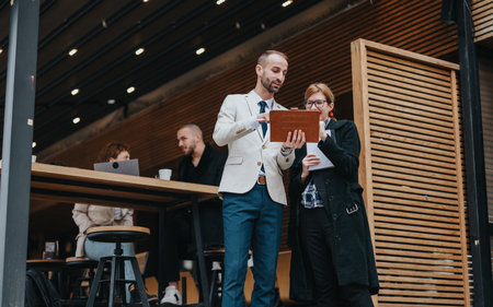 Two people discussing work outdoors at a modern casual cafeの写真素材