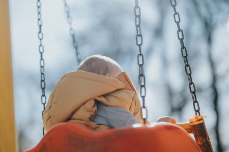 Child on a swing at a park enjoying a sunny day outdoorsの写真素材