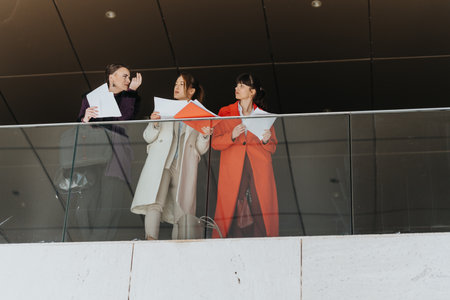 Three Businesswomen Engaged in a Discussion in a Modern Office Spaceの写真素材