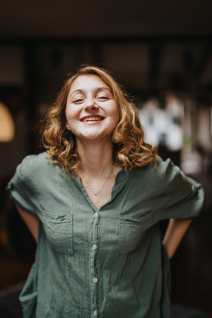 Smiling Woman in Green Shirt Radiates Happiness Indoorsの写真素材