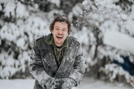 Happy man enjoying playful winter day with fresh falling snow outdoorsの写真素材