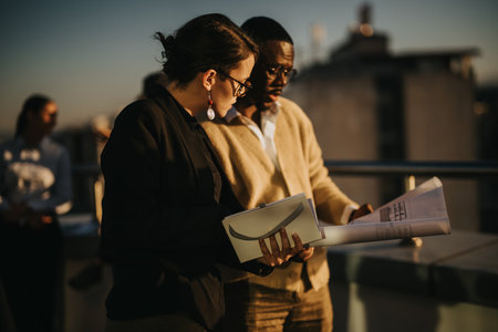 Diverse business colleagues collaborating on rooftop at sunsetの写真素材