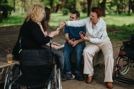 A group of friends enjoying a game of cards in a park on a sunny day, fostering community and companionship.の写真素材