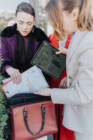 Business professionals discussing documents and technology outdoorsの写真素材