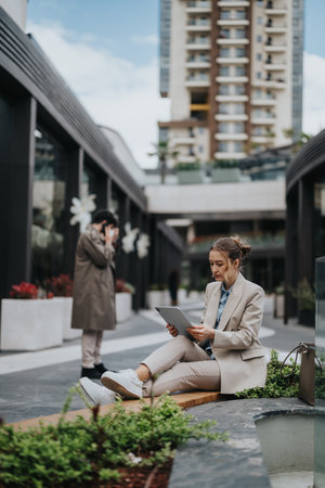 Business Casual Woman Working on a Tablet Outdoors Near Office Buildingsの写真素材