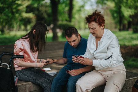 A family enjoying a card game together on a park bench during a sunny day