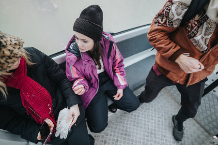 Three people sitting together in winter clothing inside a gondola cabin during a snowy outdoor excursionの写真素材