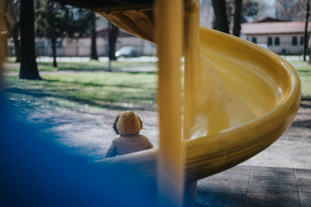 Child Wearing a Coat Enjoying a Day at the Playgroundの写真素材