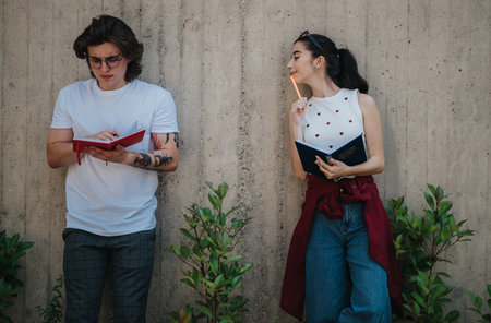 College students reading outdoors and discussing ideas while taking notes togetherの写真素材