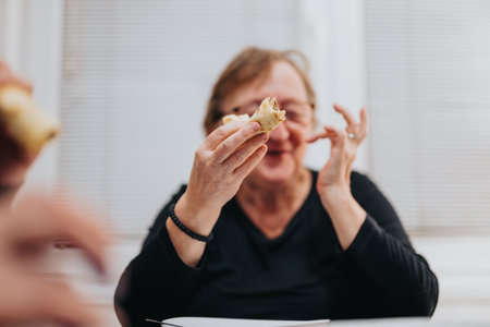 Senior woman enjoying a homemade pastry in an inviting indoor settingの写真素材