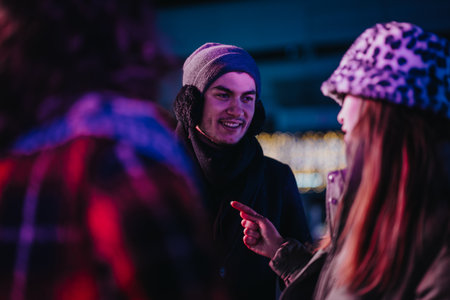 Group of friends enjoying a conversation during a winter evening light displayの写真素材
