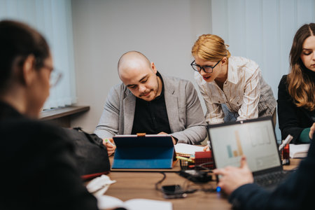 Business people collaborating during a team meeting, using technology and notesの写真素材