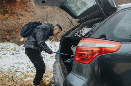 Man searching his car trunk in a rugged outdoor settingの写真素材