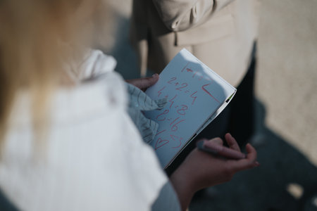 Person holding a notebook with handwritten math and illustrations outdoorsの写真素材