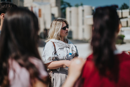 Group of students attentively listening to their professor outdoors in the sunlightの写真素材