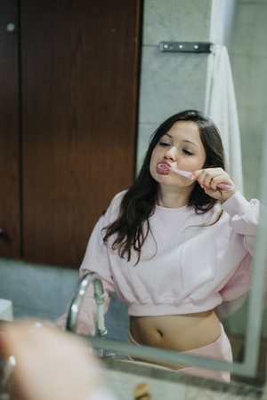 Young woman brushing her teeth in a modern bathroom setting