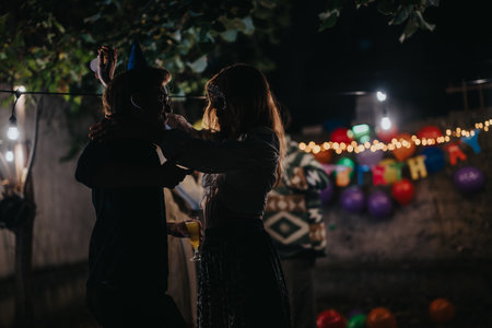 Two people dancing under lights at a festive outdoor birthday partyの写真素材