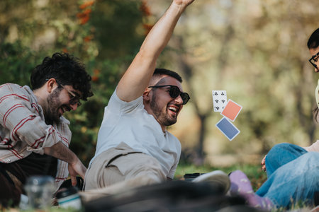 Friends laughing and playing cards during a relaxing outdoor picnic