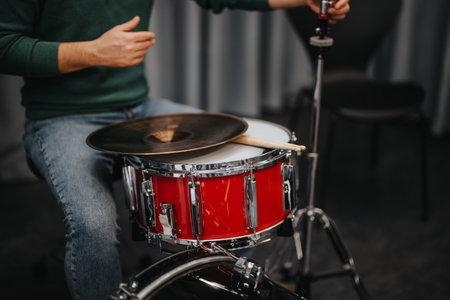Close-up of red drum kit with sticks and cymbal indoorsの写真素材