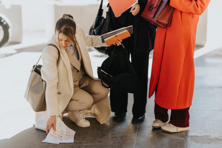 Three professional women organize documents outdoors in urban business attire.