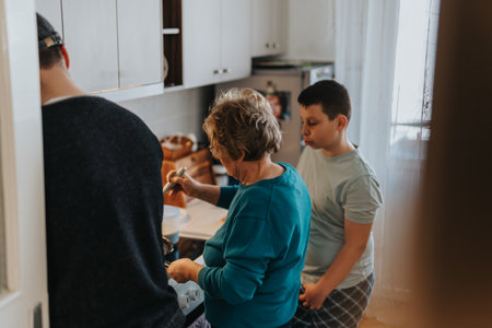 Elderly woman cooking in a home kitchen with family members attentively observing and assisting.の写真素材
