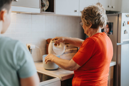 Elderly woman baking in the kitchen while teaching grandchildrenの写真素材