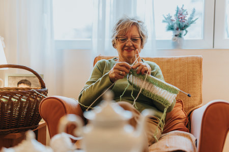 Senior Woman Knitting While Relaxing in a Comfortable Chair at Homeの写真素材
