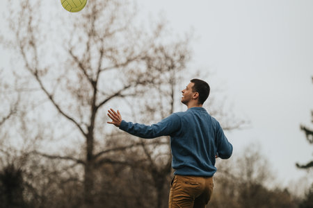 Man outdoors playing volleyball with a serene natural landscape in the background.の写真素材