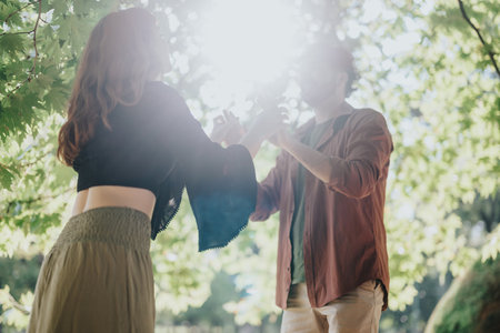 Young couple enjoying sunshine under forest canopy on a bright dayの写真素材