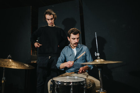 Musician Practicing Drums While Receiving Guidance in a Studio Settingの写真素材