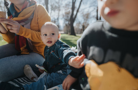 Family enjoying a sunny day outdoors with children during a picnicの写真素材