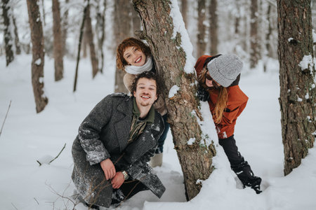 Friends enjoying a playful moment together in a snowy forestの写真素材