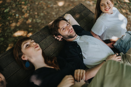 Three friends enjoying time together on a bench in a natural settingの写真素材