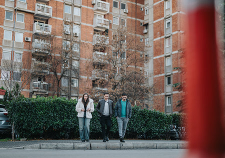 Group of friends walking outdoors near a residential building and greeneryの写真素材