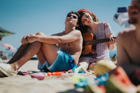 Friends enjoying a sunny day at the beach with music and laughterの写真素材