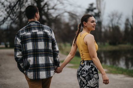 Couple walking hand in hand outdoors in a park settingの写真素材