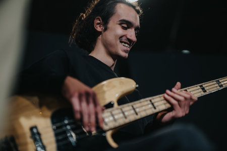 Musician playing bass guitar during band rehearsal captured in a studio settingの写真素材