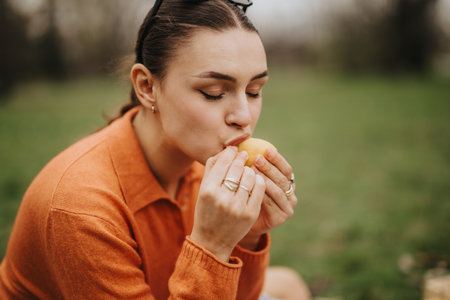 Young woman enjoying a healthy snack outdoors in a serene settingの写真素材