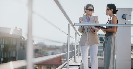 Two people discussing documents on a rooftop at sunsetの写真素材