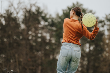 Back view of a young woman holding a yellow ball outdoorsの写真素材