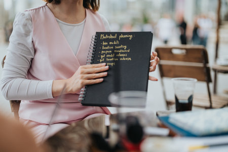 Close-up of a woman planning a photoshoot outdoors using a notebook