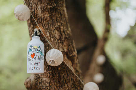 Water bottle with mountain print hangs in rustic outdoor tree settingの写真素材