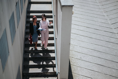 Two businesswomen walking and discussing work outdoorsの写真素材