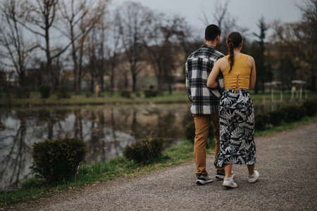 Couple leisurely walking along a pond in a serene park setting