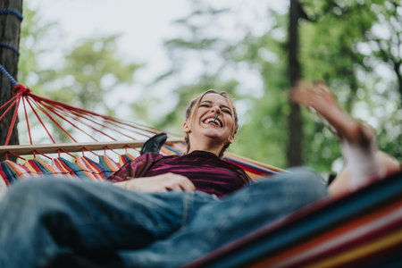 Smiling young person relaxing on a colorful hammock surrounded by lush greenery